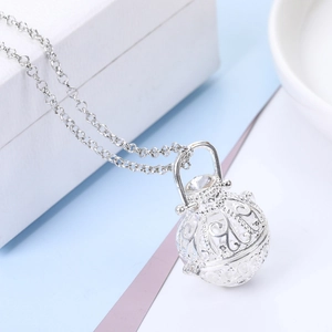 Macro shot of silver hollow ball pendant with intricate floral pattern and clear zircon