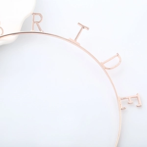 Gros plan détaillé du serre-tête Bride en métal or rose avec des lettres polies pour le mariage