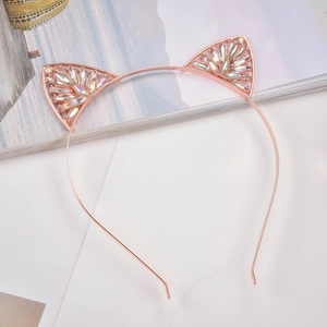 Dettaglio del cerchietto con orecchie di gatto in oro rosa e strass colorati su una rivista