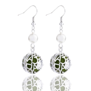 Detailed macro view of silver hollow ball earrings with green felt insert and pearl
