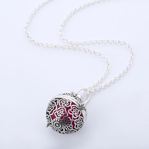 Detailed view of silver rose hollow pendant with a red inner bead and cross chain