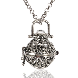 Silver filigree aroma diffuser necklace with crystal bead on white reflective background