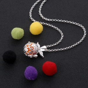 Detailed view of vintage hollow metal pendant with orange bead and silver wing charm