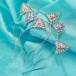 Dettaglio di tre cerchietti orecchie da gatto in oro, argento e oro rosa con cristalli