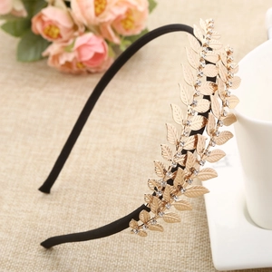 Baroque golden leaf headband with rhinestones on a textured neutral background