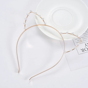 Detail of a golden cat ear headband with elegant pearl beads on a white background