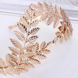 Detailed macro view of golden leaf branch bridal tiara on white stone surface
