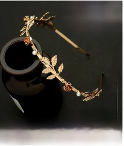Close-up of golden floral headband with metal leaves and imitation pearls on a bottle