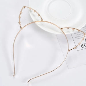 Close-up of golden cat ear headband with white pearls on a minimalist white surface