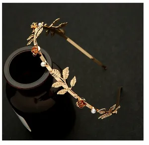 Close-up of golden leaf and rose headband featuring pearl accents and metallic details