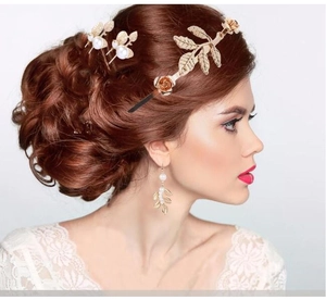 Close-up of a bridal gold leaf hairband with pearl flower accents and matching earrings