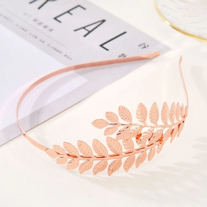 Detail of rose gold bridal leaf headband featuring textured double leaves on white surface