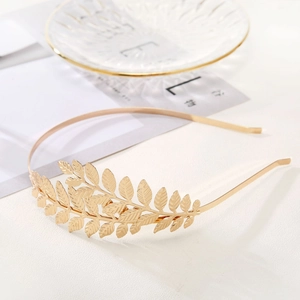 Detailed view of layered golden metallic leaf bridal headband on a textured surface