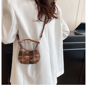 Detail of plaid crossbody bag with brown bows and lace trim worn with white blazer