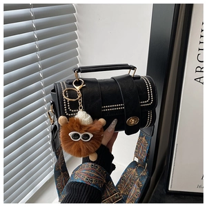 Detail of black crossbody bag with gold studs and colorful ethnic style shoulder strap
