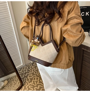 Detail of cream fabric bucket bag with brown leather trim and cute bear charm accessory