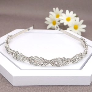 Macro detail of bridal crystal headband with leaf patterns on a white podium