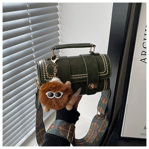Detail of dark green retro cylinder bag with gold rivets and wide patterned shoulder strap