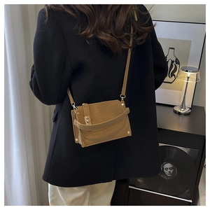 Detailed view of a vintage tan crossbody bag featuring a metal twist lock on a female model