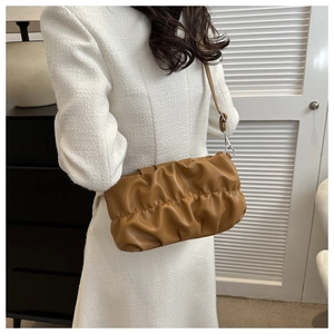 Vue détaillée d'un sac nuage marron plissé en cuir souple porté à l'épaule par un mannequin