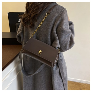 Detail of dark brown leather crossbody bag featuring gold twist lock and chain strap