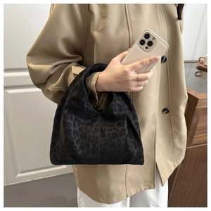 Détail d'un sac à main en satin à motif léopard noir porté par un mannequin avec style