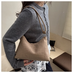 Detail of camel woven texture tote bag featuring minimalist cylindrical strap with silver hook