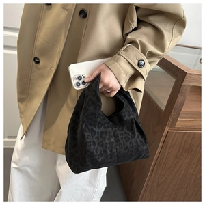 Detail of trendy black leopard print hobo handbag held by model for casual winter look