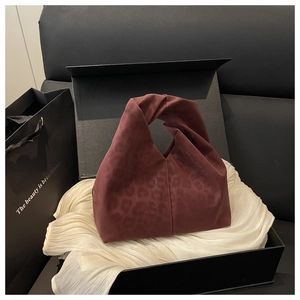 Detail einer weinroten Knotentasche mit Leopardenmuster in einer Geschenkbox