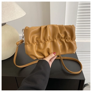 Détail du sac nuage plissé caramel avec bandoulière réglable dans un décor de maison