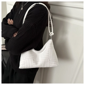 Close-up of white padded woven tote bag showing texture and decorative knotted shoulder strap