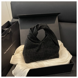 Detail einer schwarzen Handtasche mit Leopardenmuster und Knotengriff in Geschenkbox