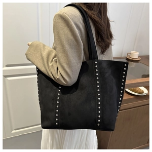 Detail of black suede tote bag with silver rivets styled with a casual winter outfit