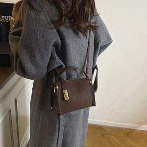 Structured dark brown leather crossbody bag with top handle and gold metal buckle