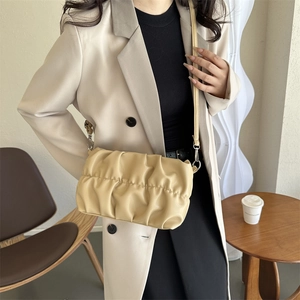 Sac à bandoulière froncé beige minimaliste pour femme dans un décor moderne chic