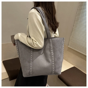 Detailed view of gray large capacity tote bag with silver studs on casual outfit