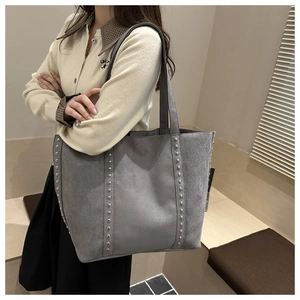 Detail of grey suede tote bag featuring metallic rivets and premium matte texture