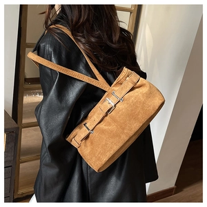 Détail du sac à bandoulière en daim marron avec boucle en métal sur une veste en cuir noir