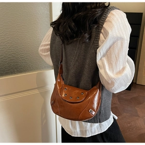Détail du sac demi-lune en cuir marron avec clous métalliques et bandoulière réglable