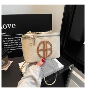 Detail of beige vintage handbag with embossed round logo and gold metal chain strap