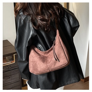 Close-up of a dusty rose suede half-moon hobo bag with long decorative fringes