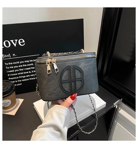 Detailed view of dark grey textured box bag with gold double zip and chain strap