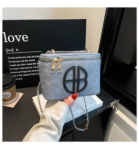 Close-up of blue denim texture box bag with black AB logo and gold chain strap