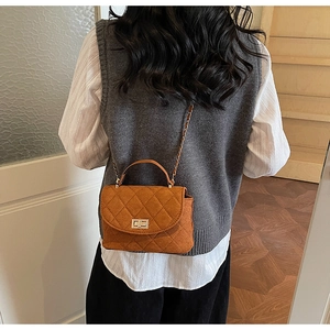 Detail of quilted brown suede crossbody bag with silver twist lock and chain strap