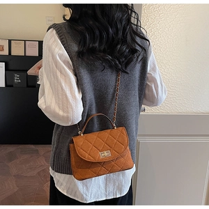 Sac bandoulière matelassé marron caramel avec fermoir tournant doré porté par mannequin