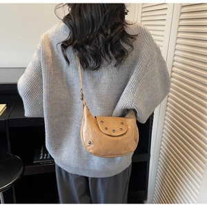 Détail du sac demi-lune en cuir PU kaki avec clous vintage porté à l'épaule