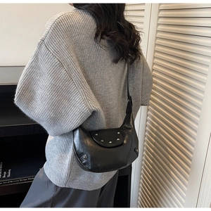 Sac hobo vintage noir à clous argentés porté avec un pull en maille gris chiné