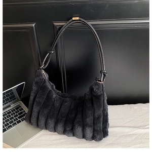 Détail du sac d'épaule en fausse fourrure noire avec plis verticaux et boucles dorées