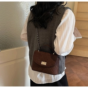 Model view of dark brown quilted crossbody bag with gold chain strap and metal lock