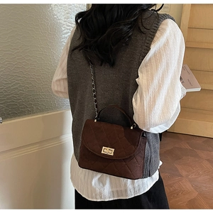 Détail du sac bandoulière en daim marron avec motif losanges et fermoir rotatif doré